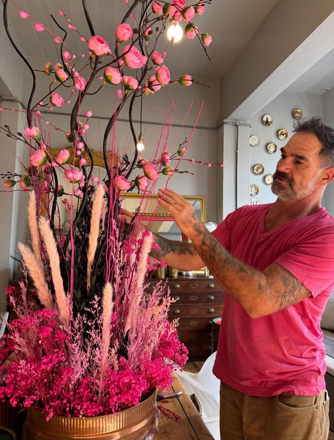 Ryan Findlay arranging a botanical installation of pink blooms and dried grasses